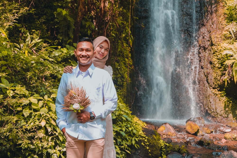 a man and woman standing in front of a waterfall