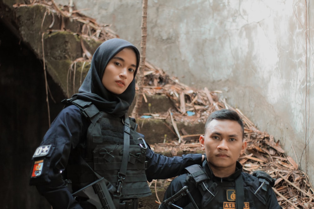 a man and woman standing next to each other in front of a rock wall