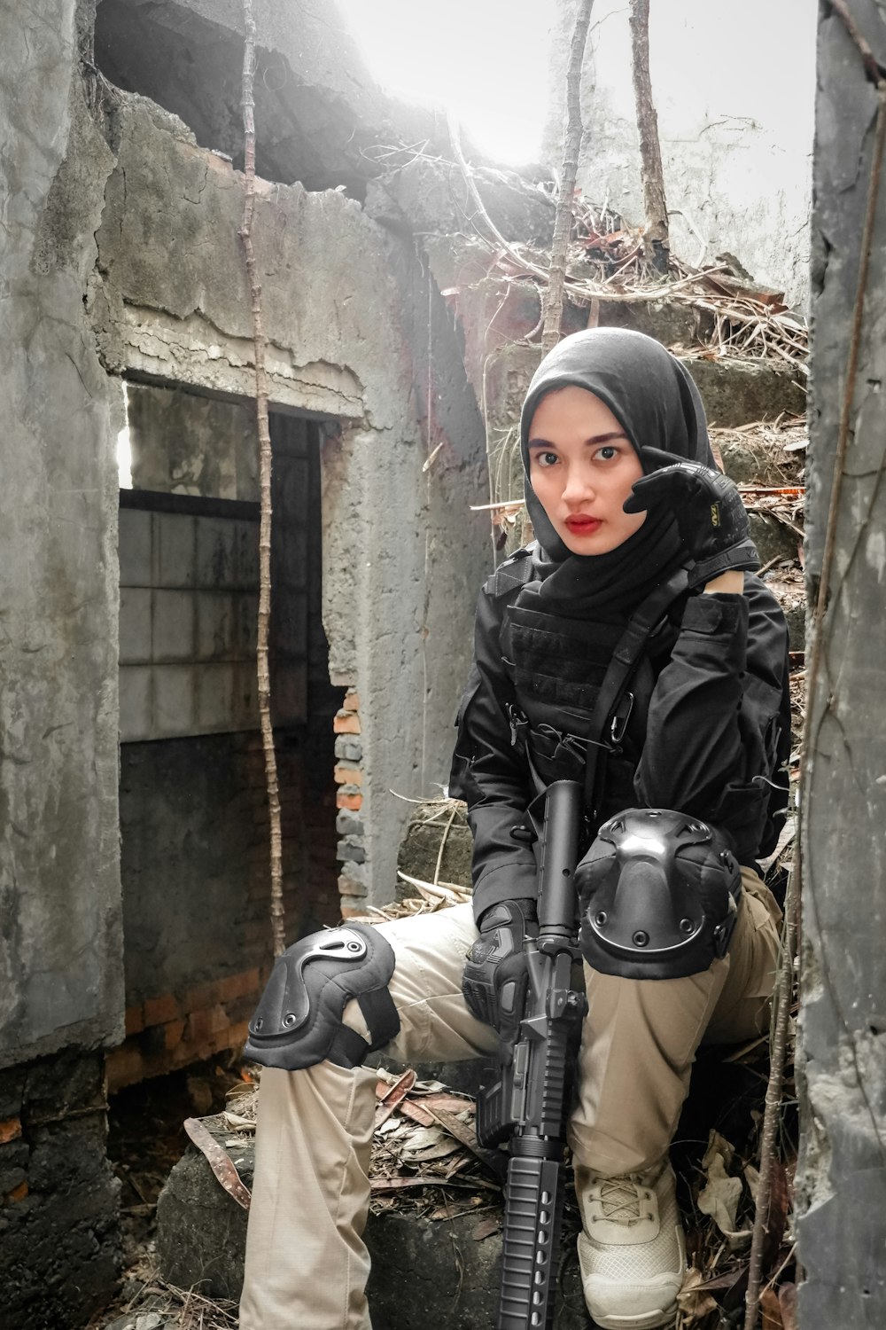 a person in a black coat holding a gun in front of a stone building