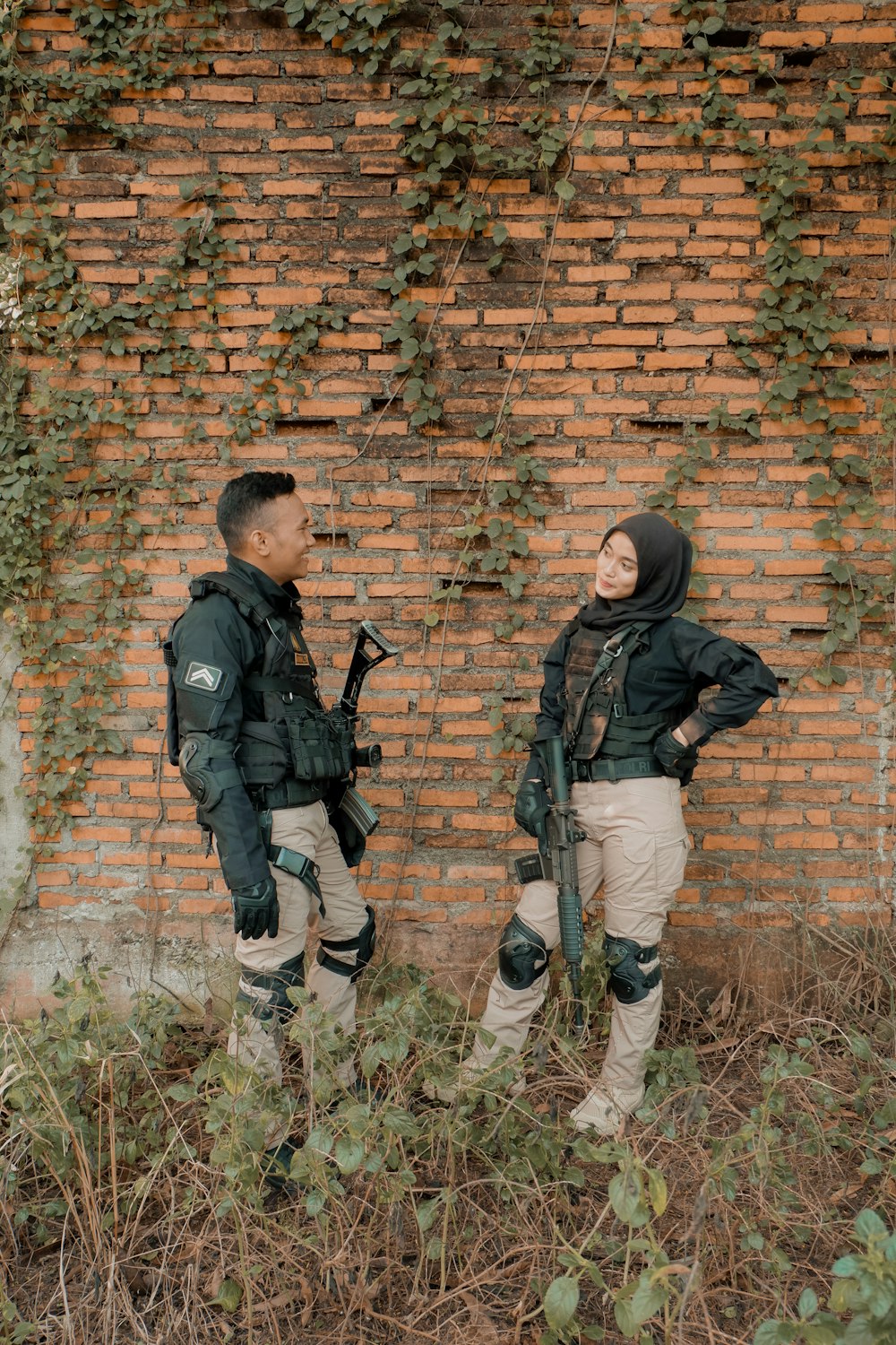 a couple of people standing next to a brick wall