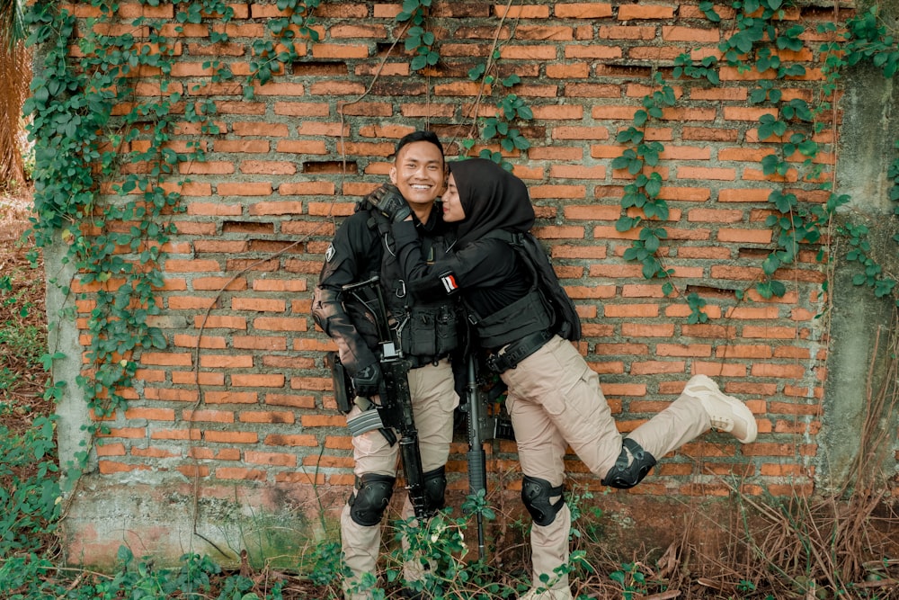 a person kneeling next to a brick wall holding a gun