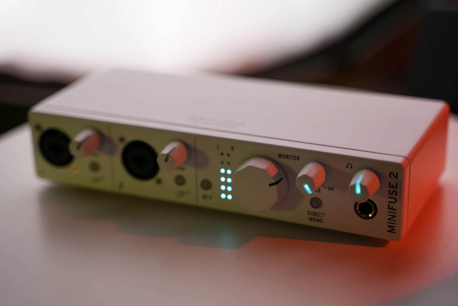 White Arturia MiniFuse 2 USB audio interface with XLR combo inputs, LED meters, and monitor knobs on a desk