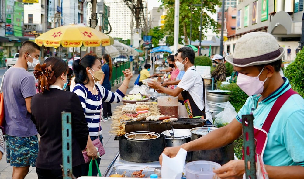 a group of people standing around a table with food on it