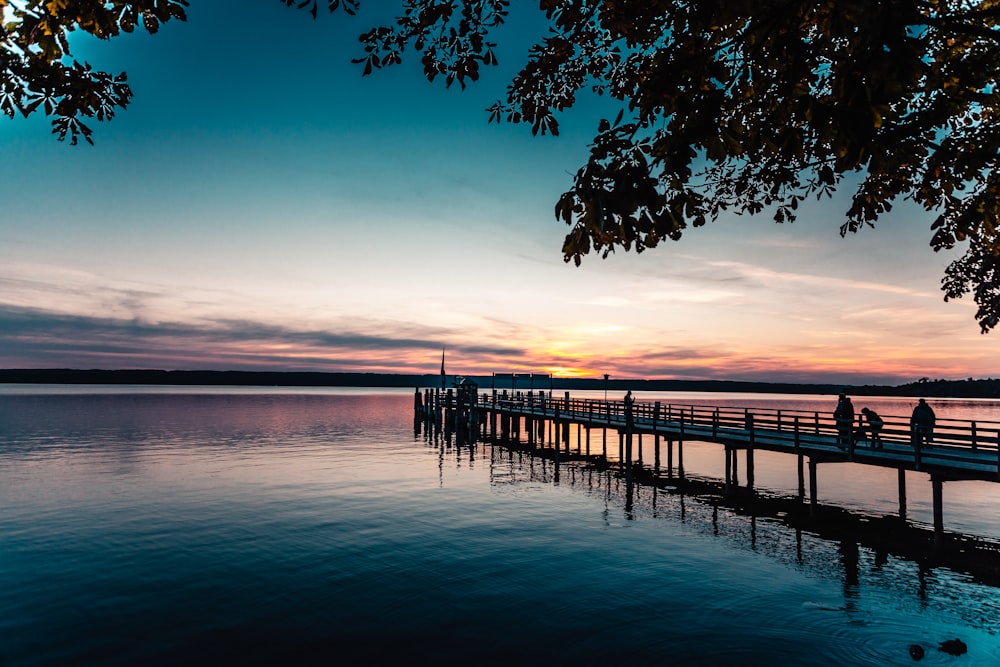 a group of people walking on a dock over water