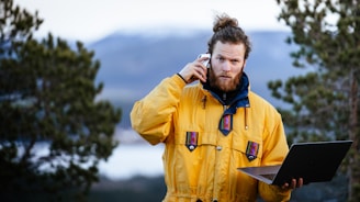 a man in a yellow jacket holding a laptop
