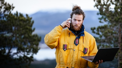 a man in a yellow jacket holding a laptop