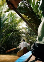 Traveler canoeing through narrow igarapés surrounded by lush green foliage and vibrant wildlife.