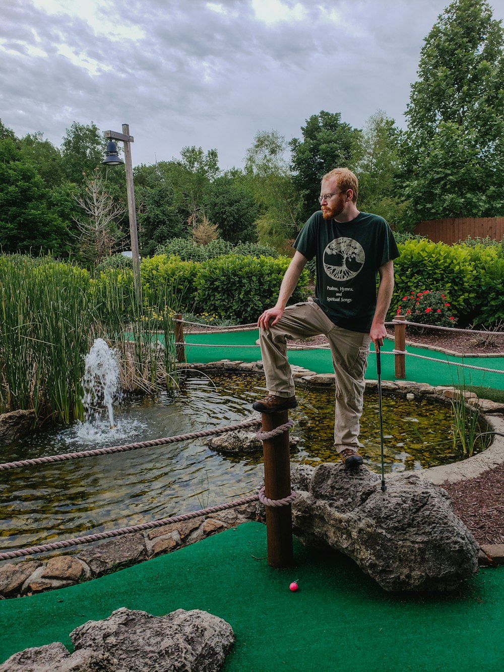 a man standing on a wooden platform near a pond