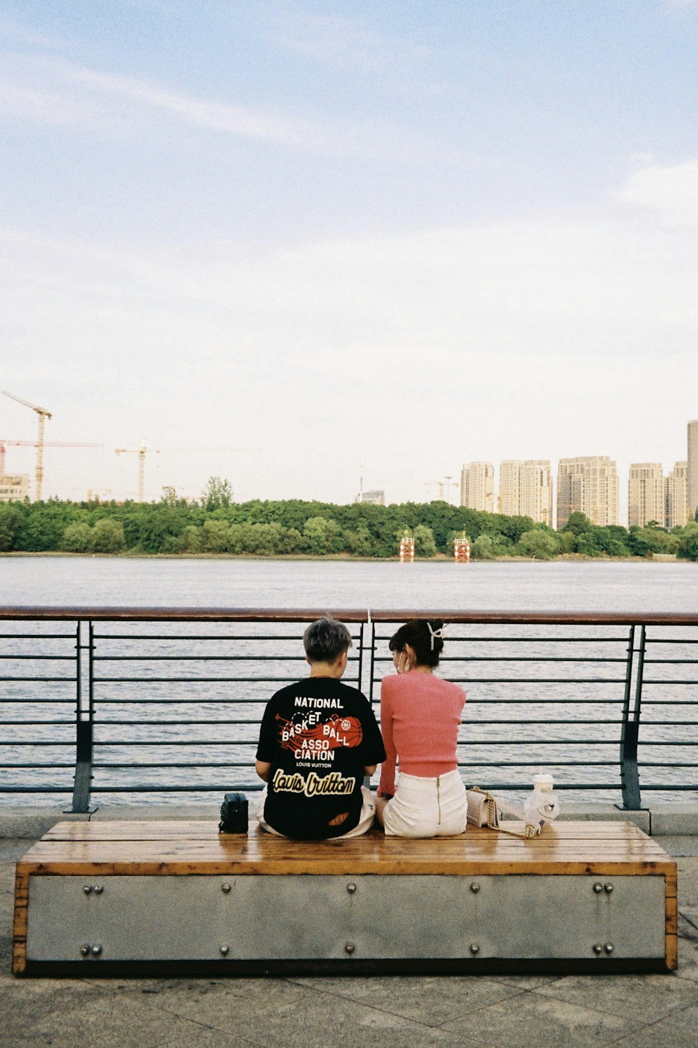 a man and woman sitting on a bench by a body of water