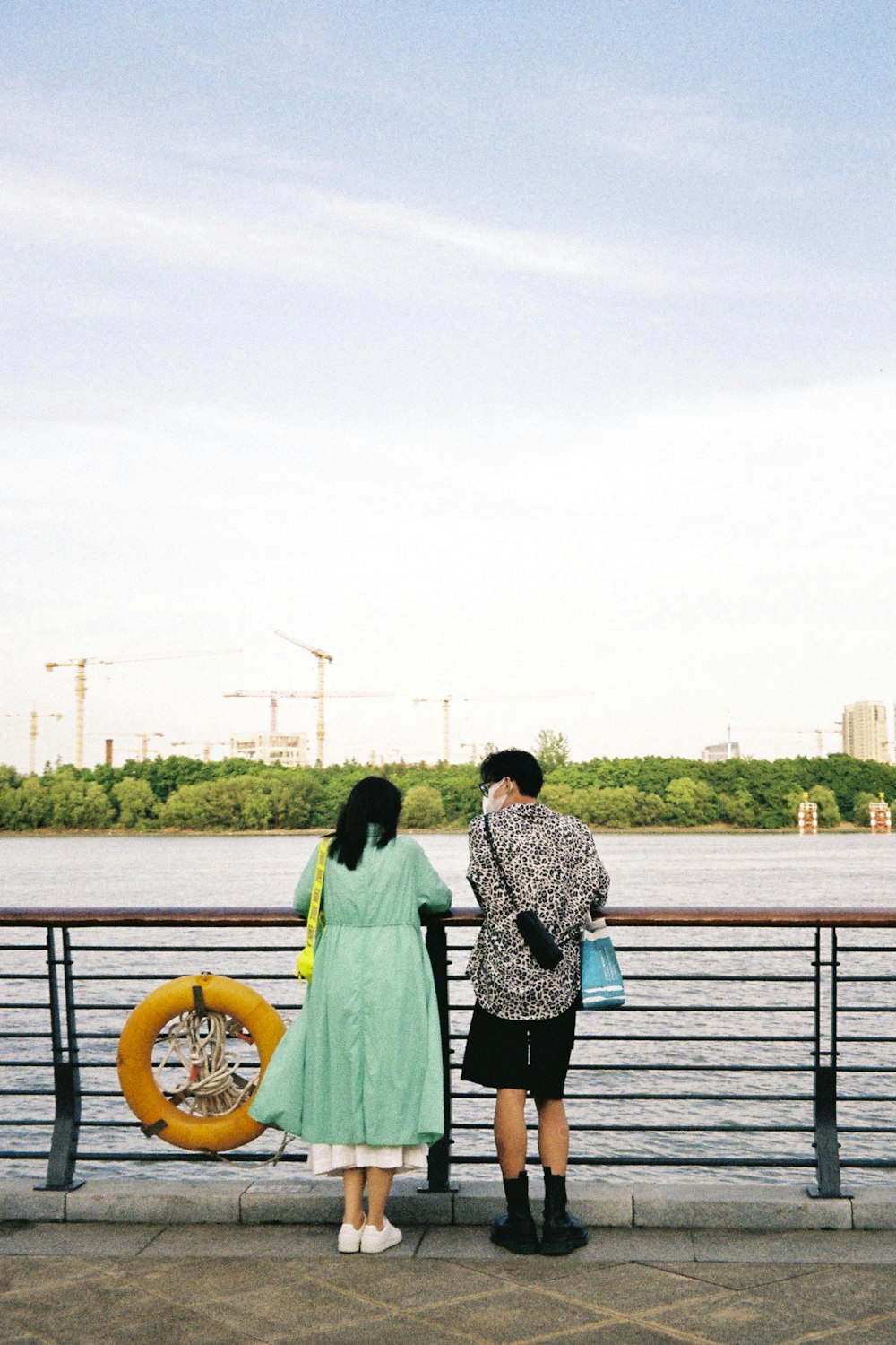 a man and woman standing on a bridge over water