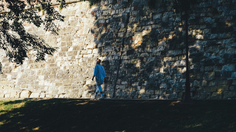 a man standing in front of a stone wall