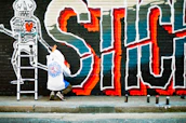Urban artist spray-painting a bold graphic on a white hoodie in a studio.