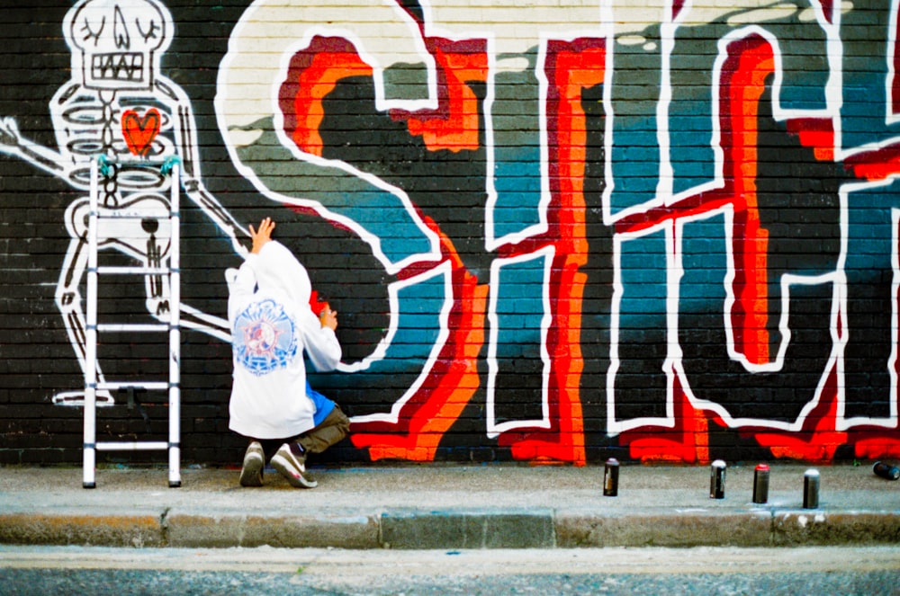 a person jumping in the air in front of a wall with graffiti