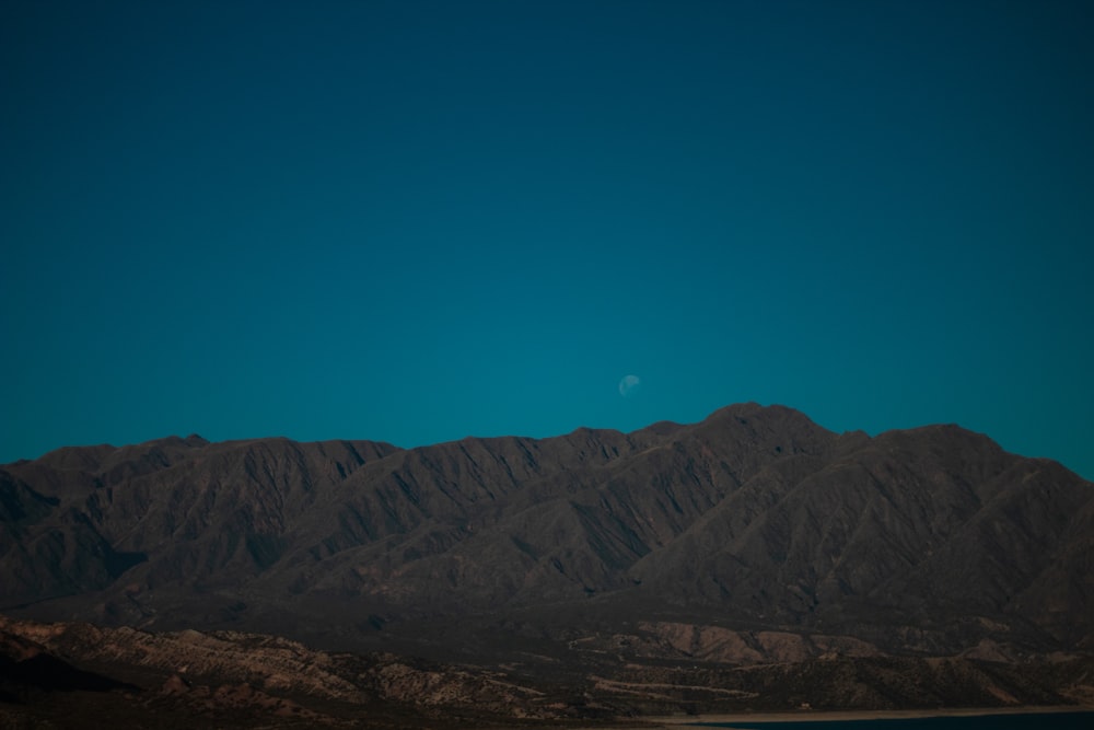 a mountain range with the moon in the sky