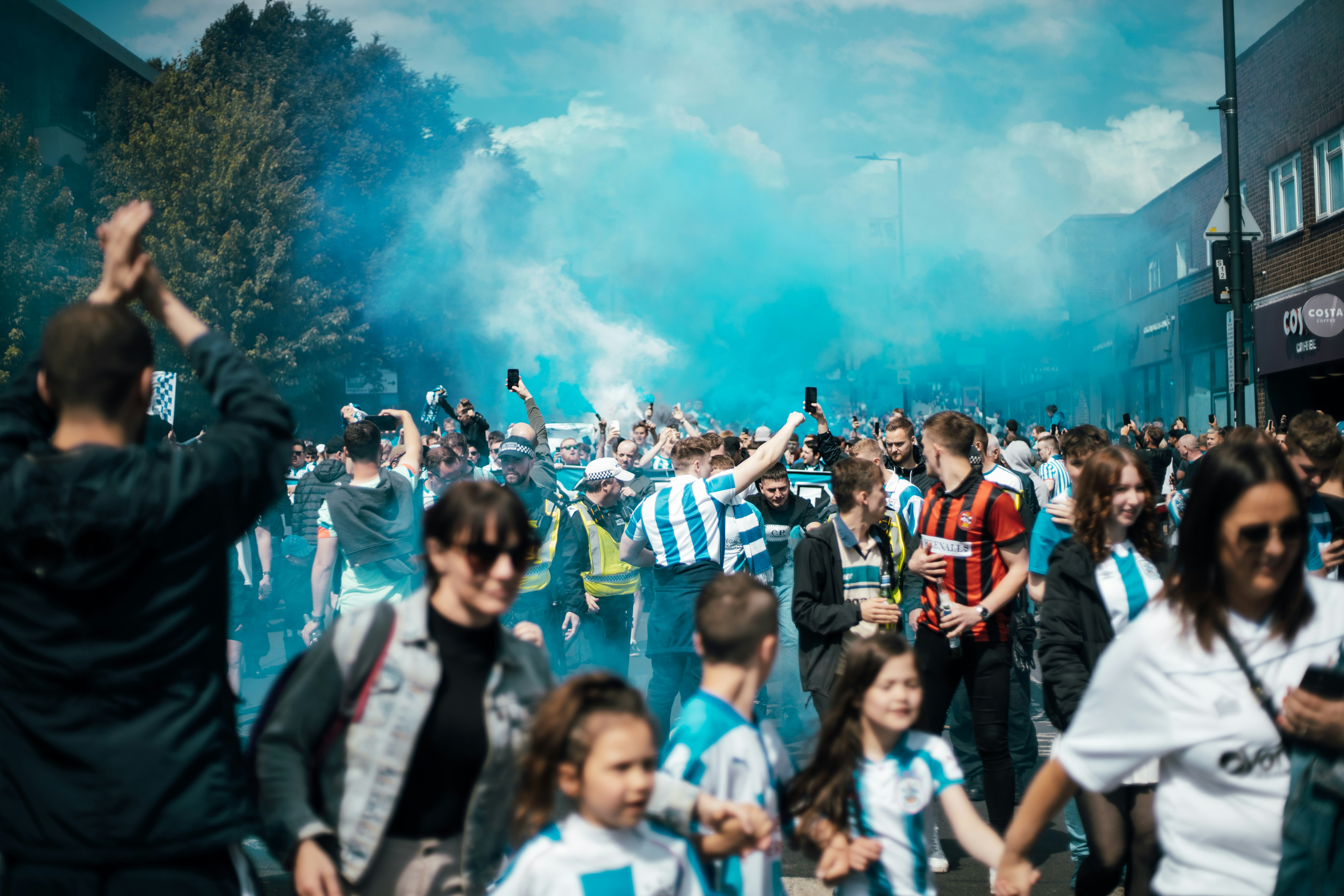 a group of people standing outside, Huddersfield Town football team fans march on Wembley for the play off finals.