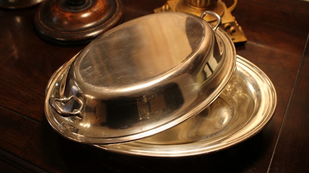 Close-up of the polished surface of a bravique chafing dish reflecting soft ambient light.