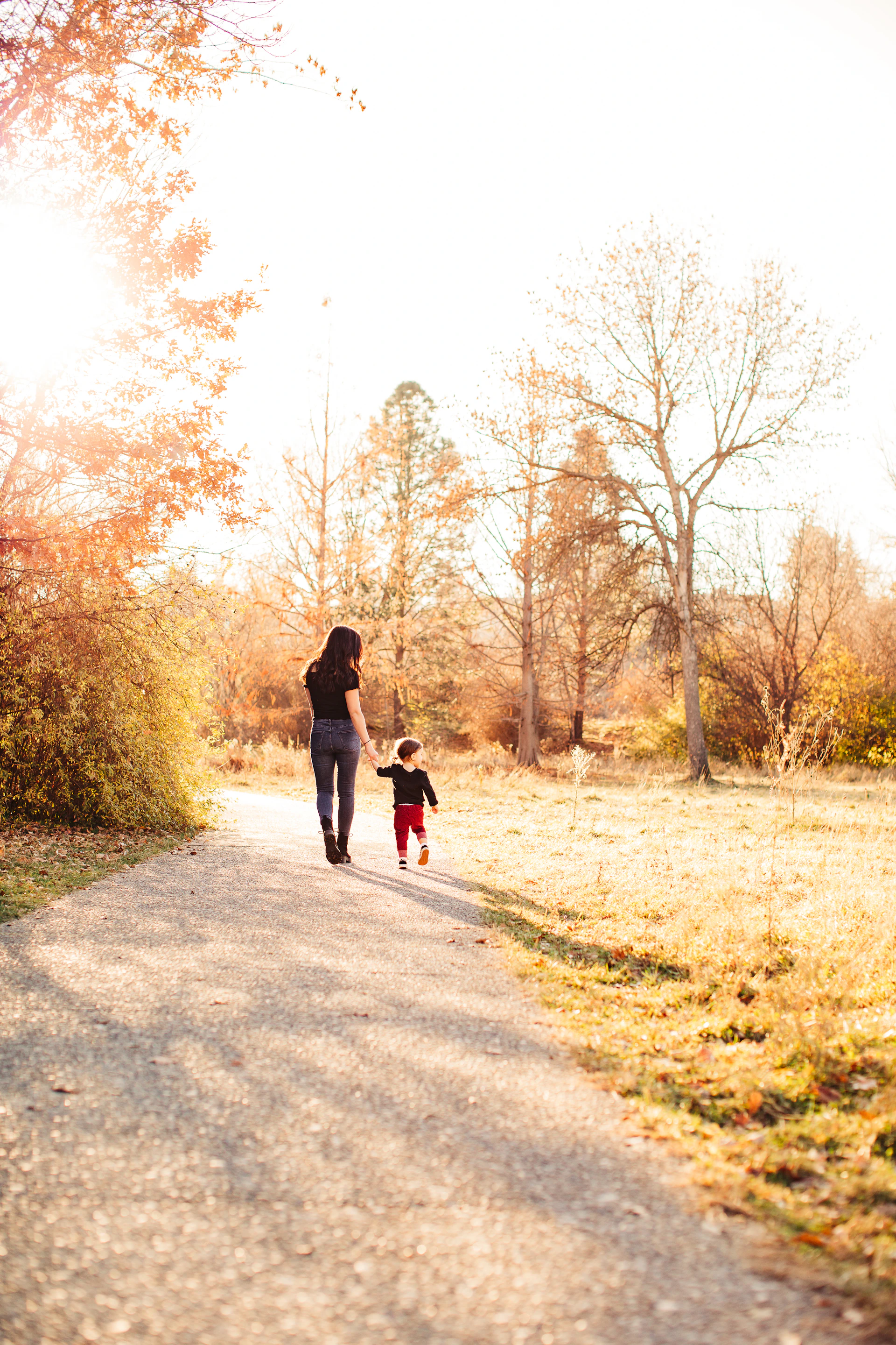 a man and a child walking on a road with trees on either side