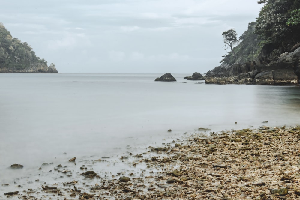 a rocky beach with a body of water and a rocky cliff