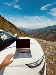 a hand holding a laptop in a remote location