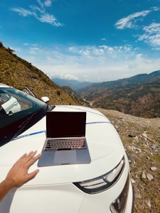 a hand holding a laptop in a remote location