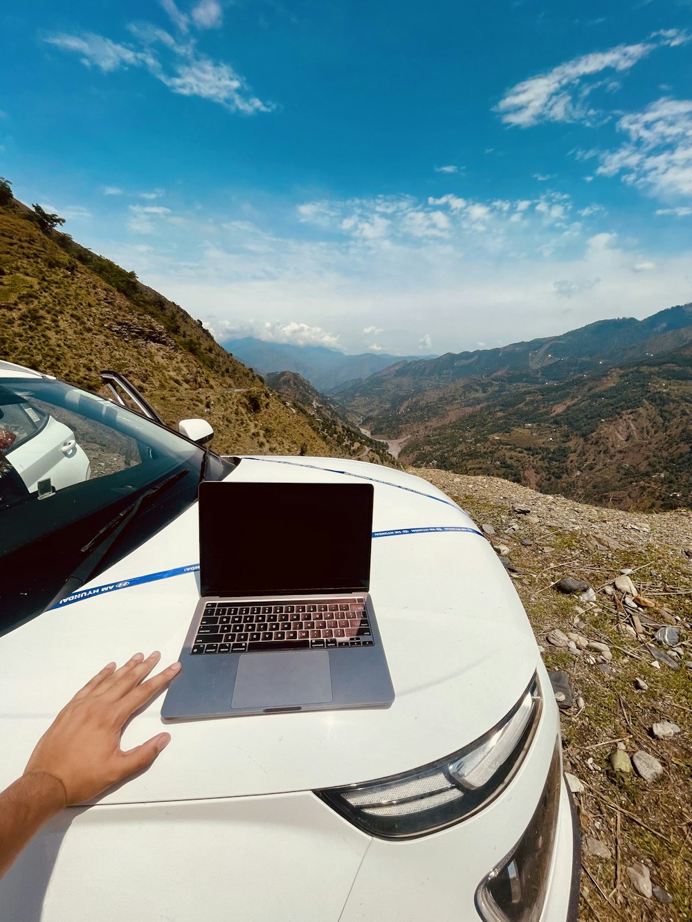 a hand holding a laptop in a car