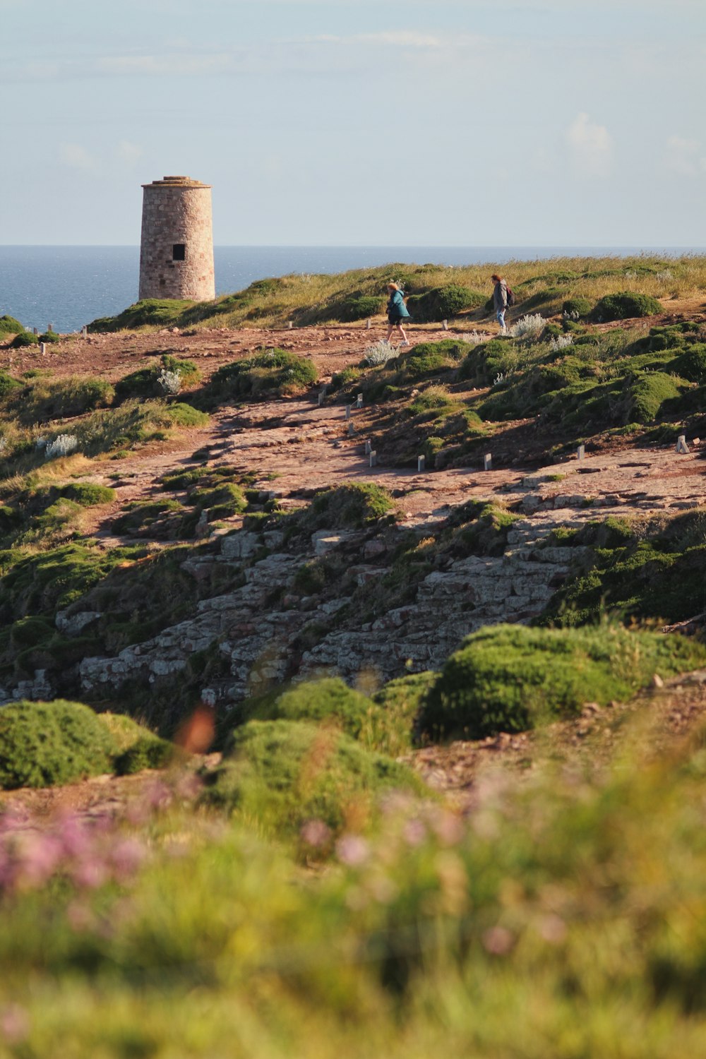 a group of people standing on a rocky hill with a tower