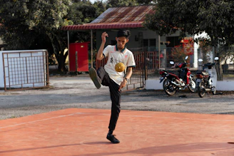Male football creator filming solo ball drills on an urban street pitch.
