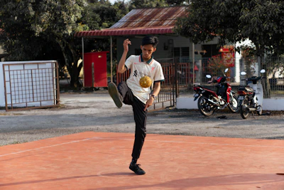 Male football creator filming solo ball drills on an urban street pitch.