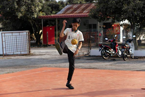 Football influencer executing sharp dribbling moves on cracked asphalt surrounded by graffiti walls