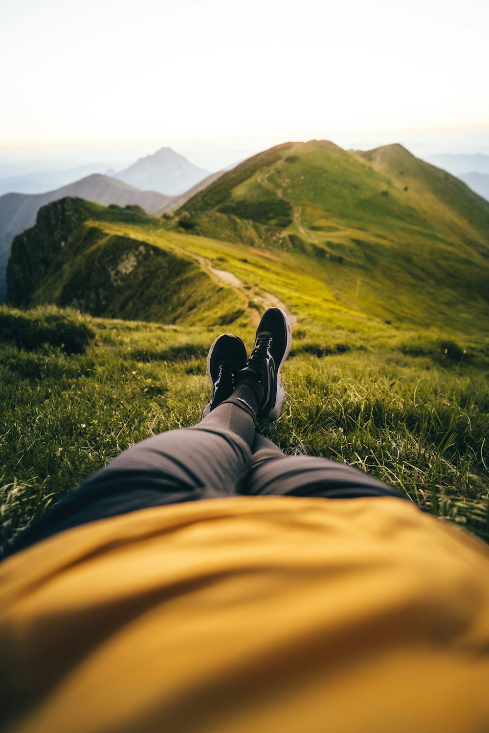 a person's legs and feet on a grassy hill