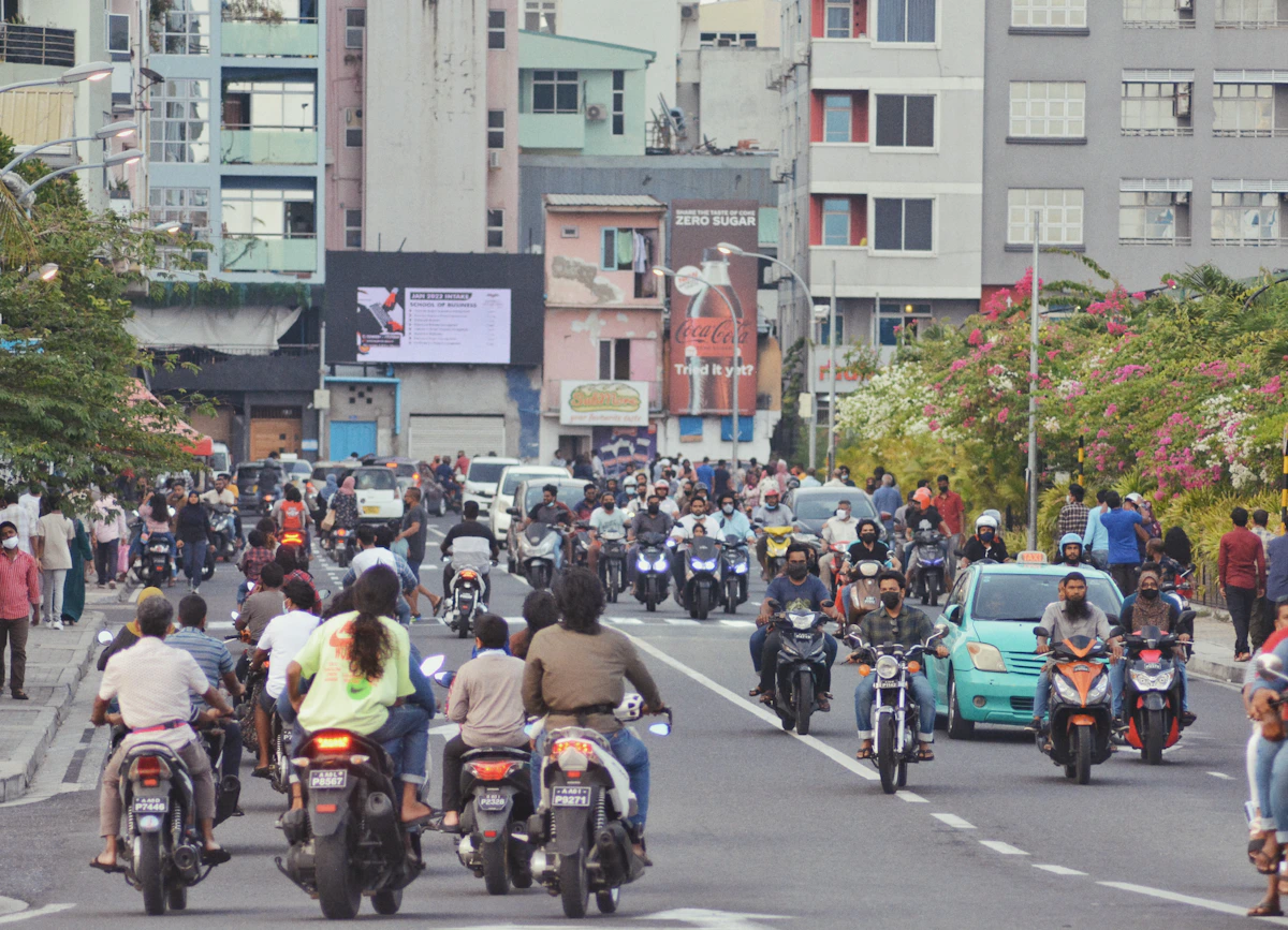Motorbikes and cars moving through a busy street in Malé