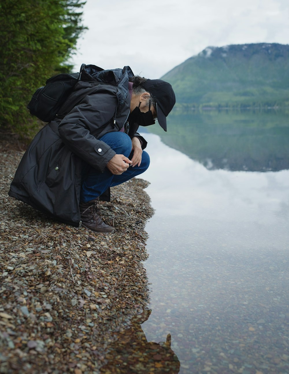 a man sitting on a rock by a body of water