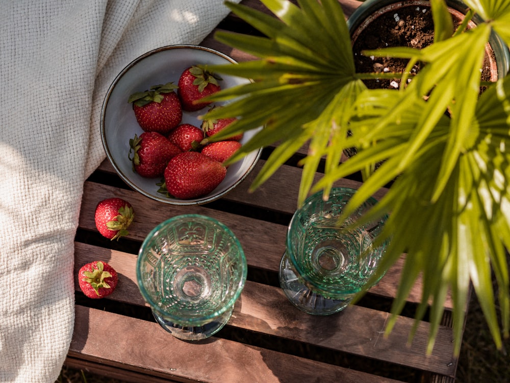 a bowl of strawberries and a glass of water on a table
