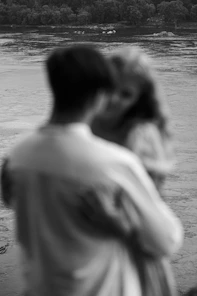 a man and woman kissing in front of a lake