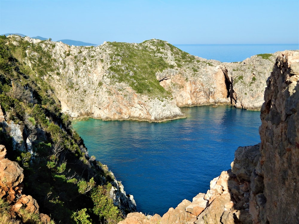 a rocky cliff with a body of water below with Calanques National Park in the background
