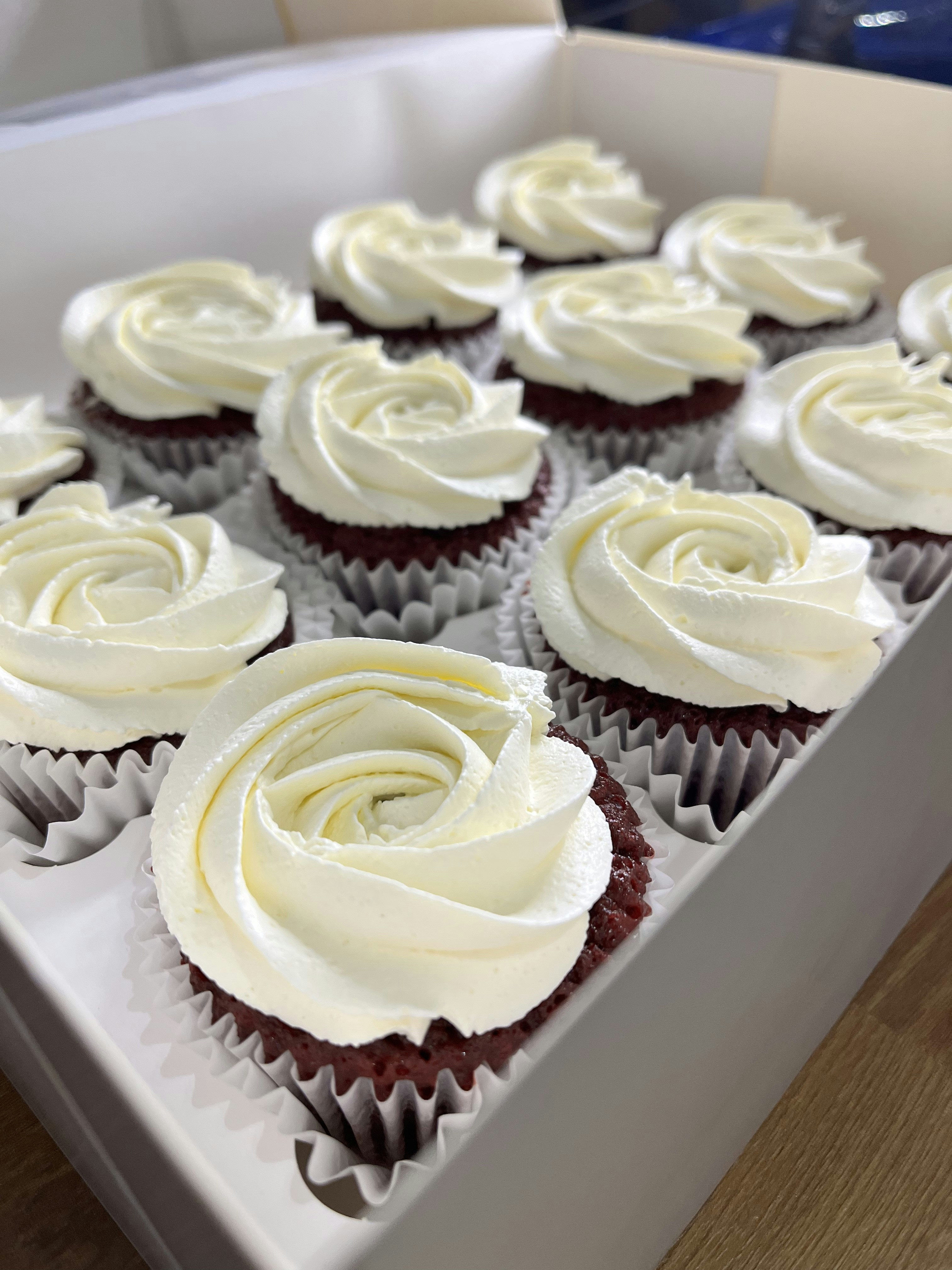 Box of 12 red velvet cupcakes in luxury gift packaging with ribbon