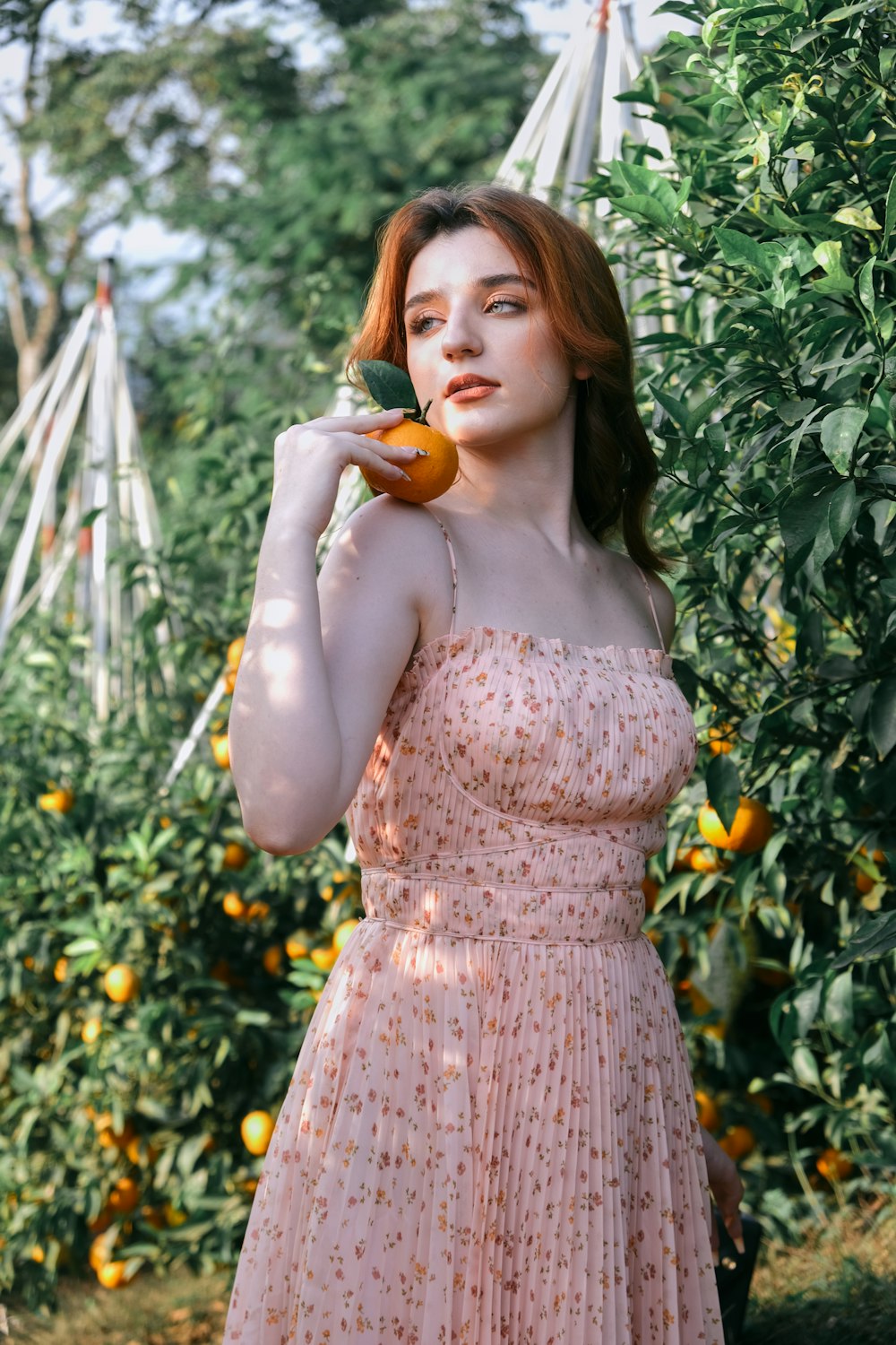 a person in a dress holding an orange object in a garden
