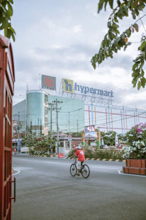 a person riding a bicycle on a street with a large building in the background