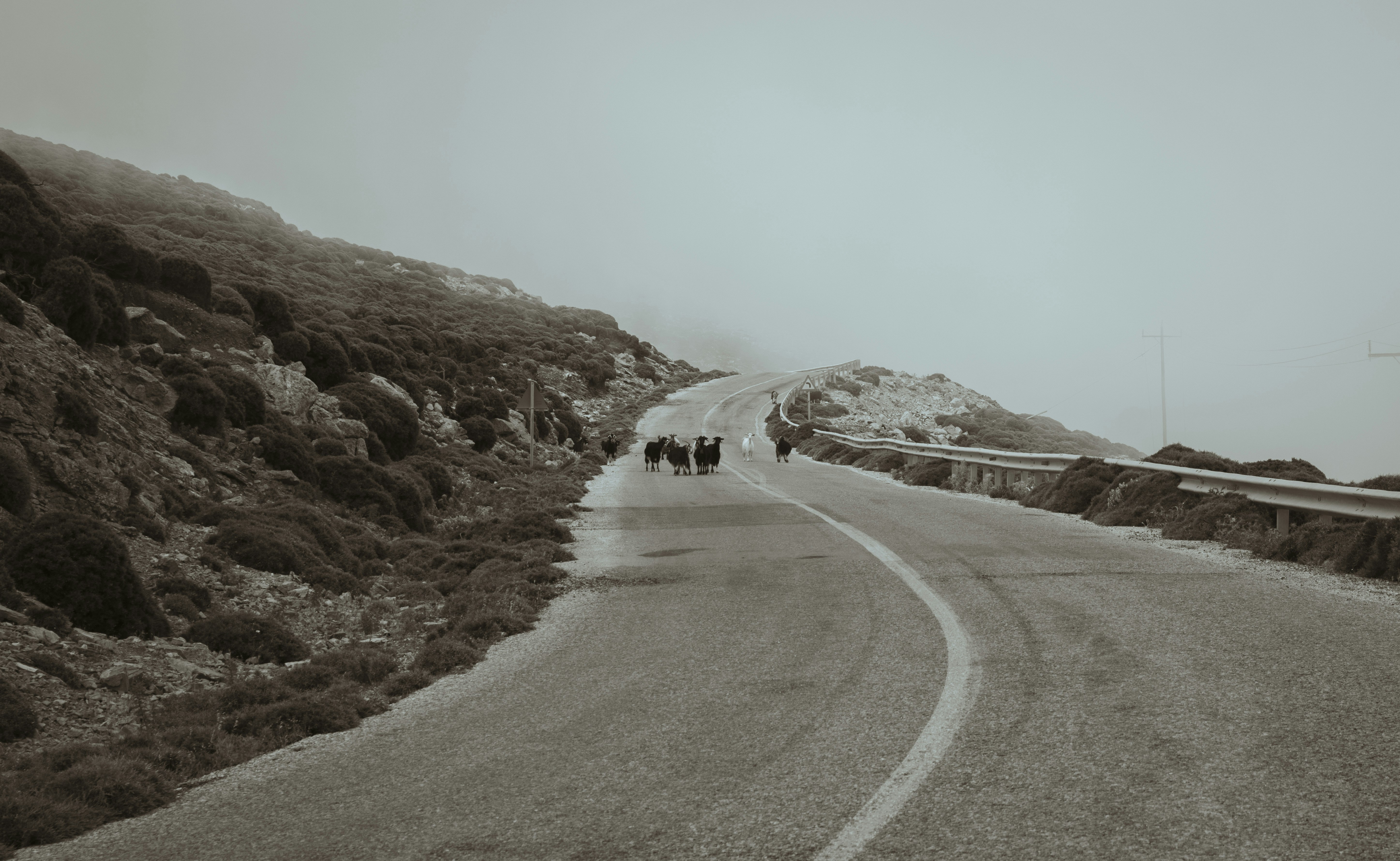 a road with a group of people on it and a hill with snow