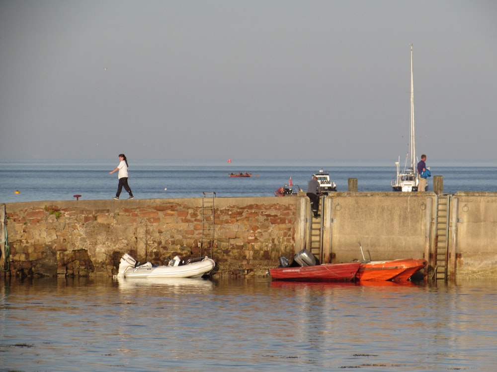 a person walking on a dock next to a couple of boats