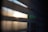 Horizontal slats of window blinds partially open, allowing light to filter through, creating a soft, diffused glow with shadows and highlights.