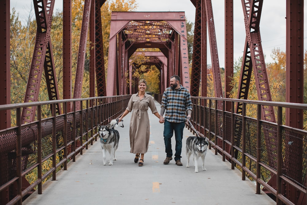 a man and woman walking dogs on a bridge