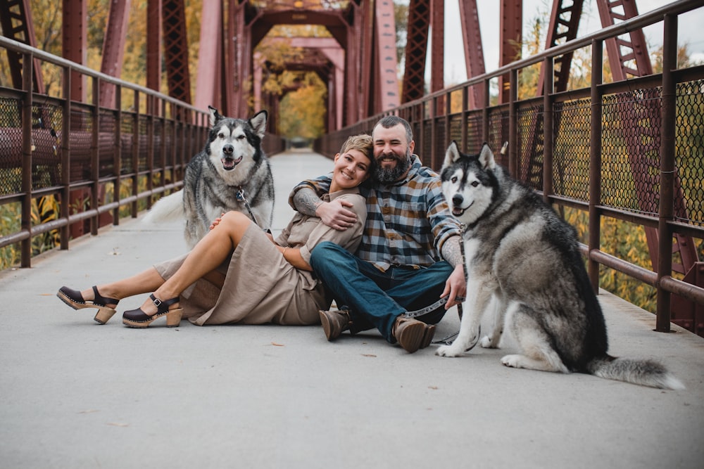 a couple of men sitting on the ground with a dog