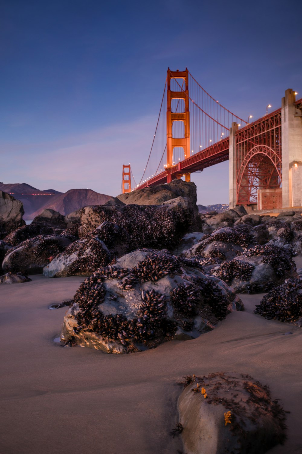 a red bridge over a rocky river