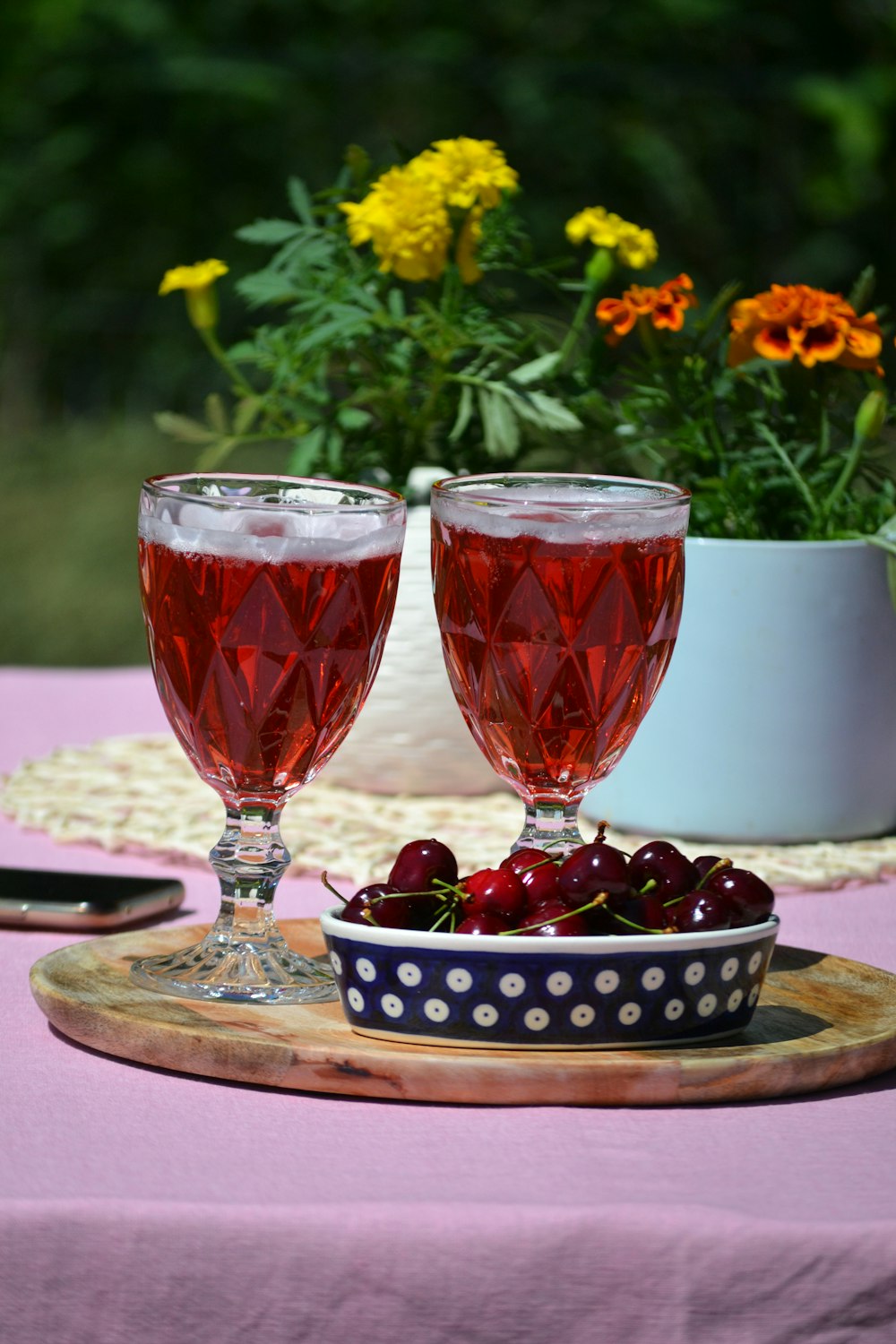 a couple of glasses with red liquid and berries on a table