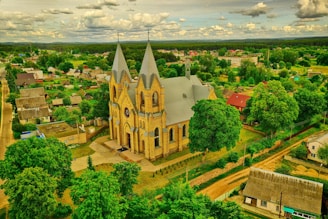 A historic stone church nestled in a quiet European village under a clear blue sky.
