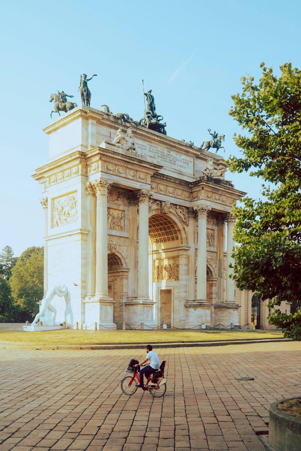 a person riding a bicycle in front of a building with statues
