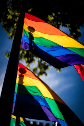 Close-up of a colorful pride flag waving gently in the sunlight.