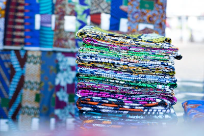 Stack of vibrant patterned fabrics ready for wholesale distribution.