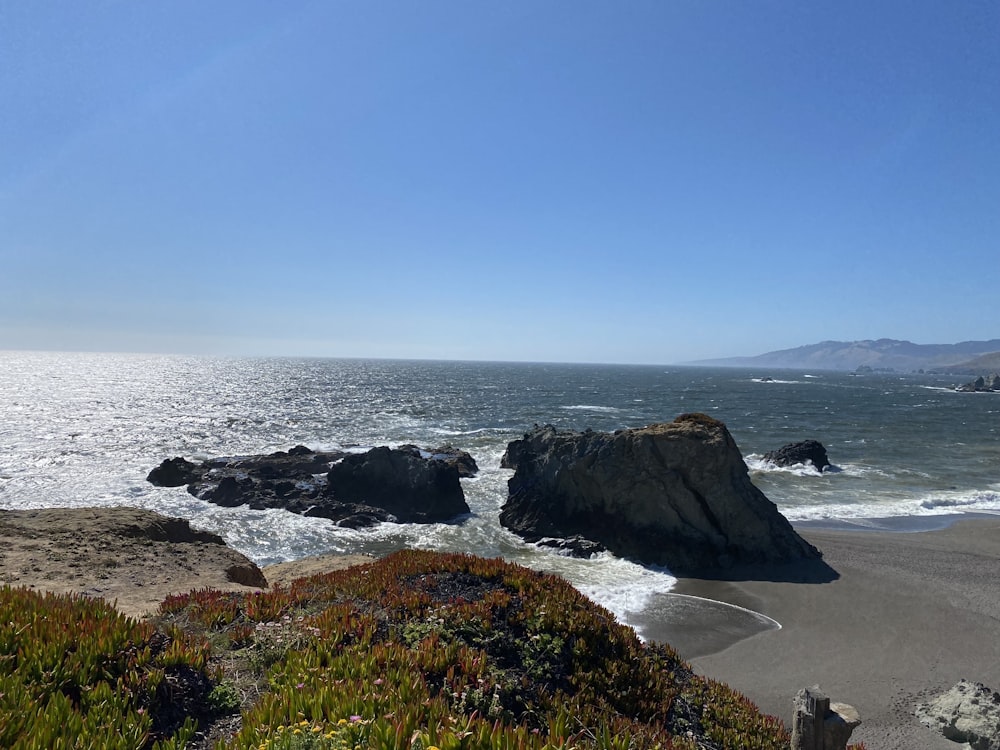 a rocky beach with a body of water in the background